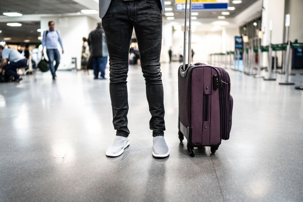 A man standing beside a suitcase